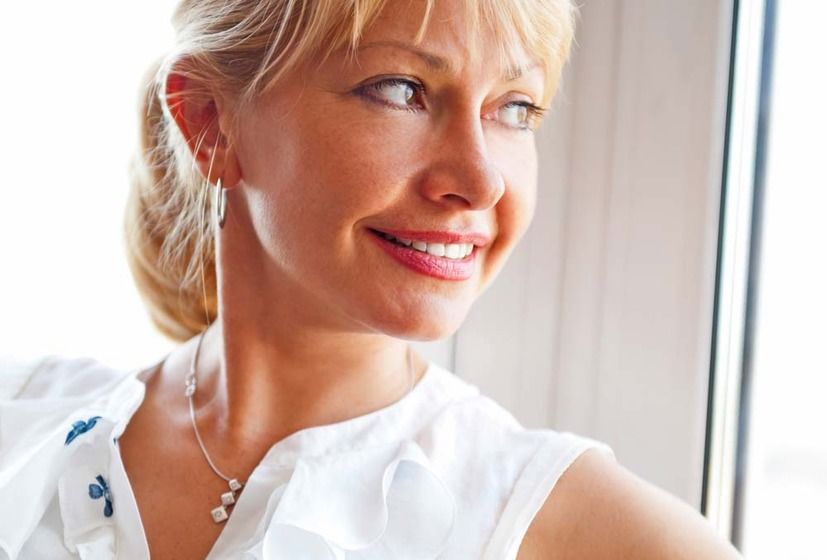 A woman smiling after getting a neck lift